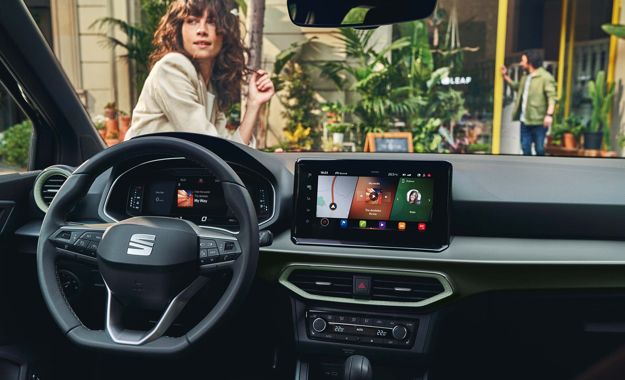 SEAT Arona 2024 interior, steering wheel, infotainment screen interface on, woman and plants in front of car