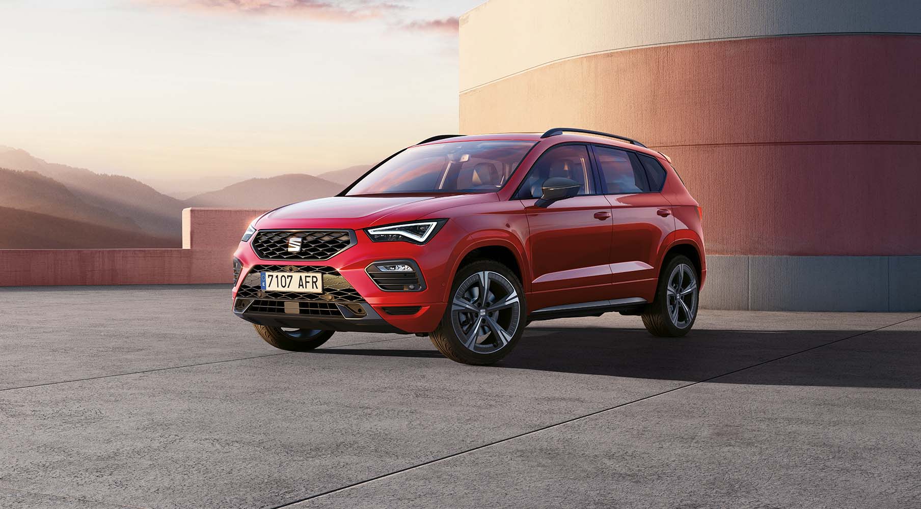 three-quarter side view of red seat ateca 2024 vehicle at sunset, parked on smoot concrete surface