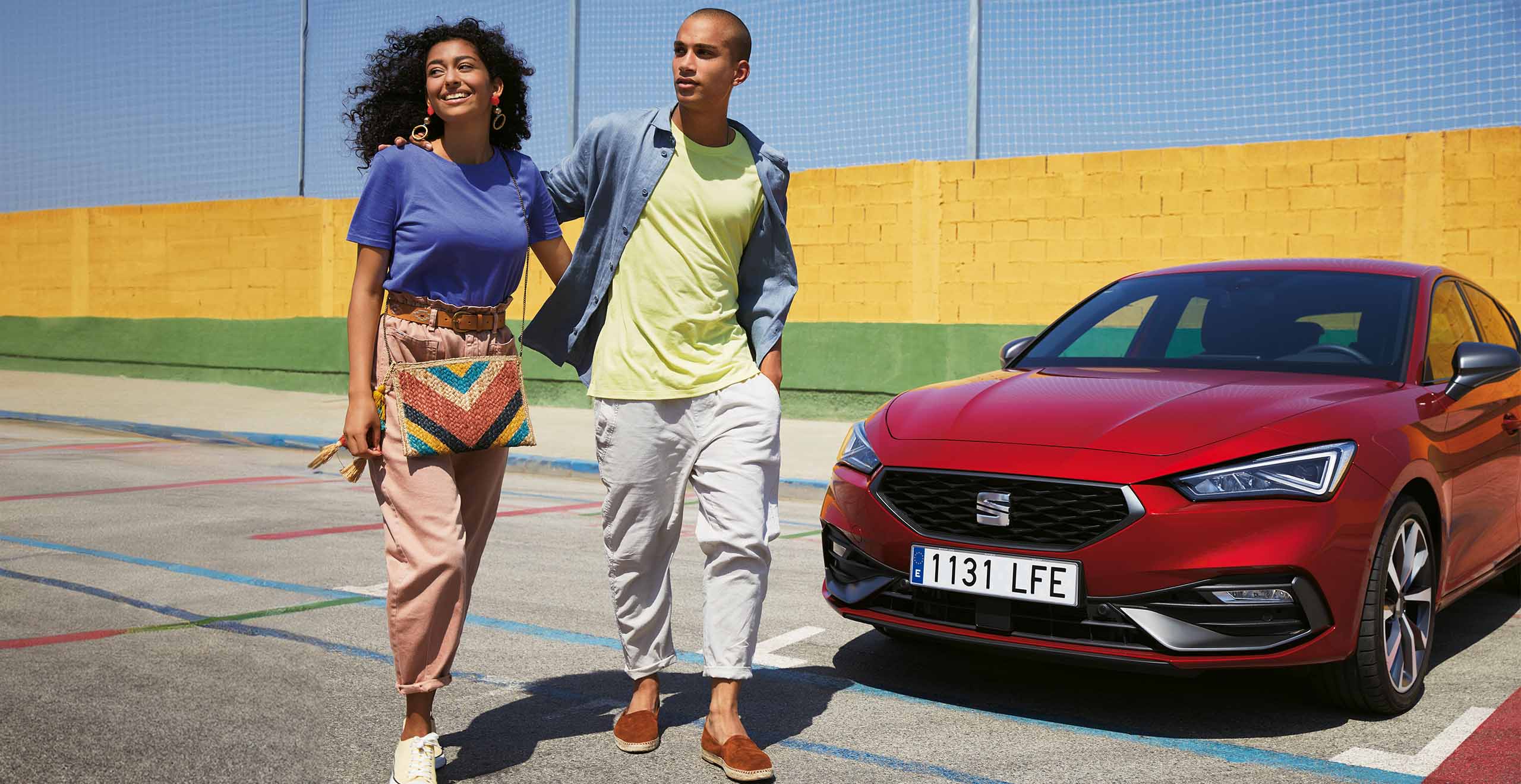 Couple talking next to a SEAT Leon desire red colour.