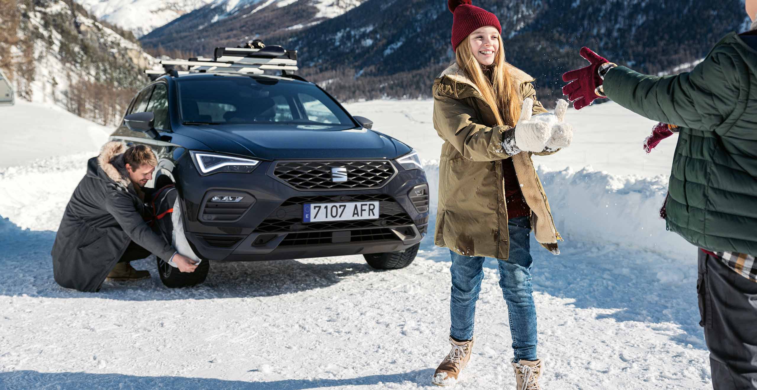 Front view of a SEAT Leon, while a couple is having a snowball fight 