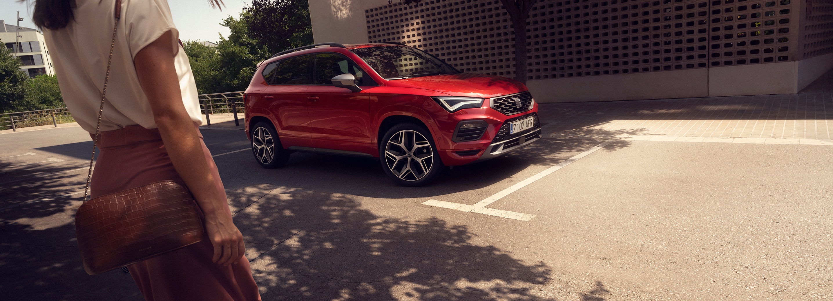 a person approaching to a red seat ateca parked in the street
