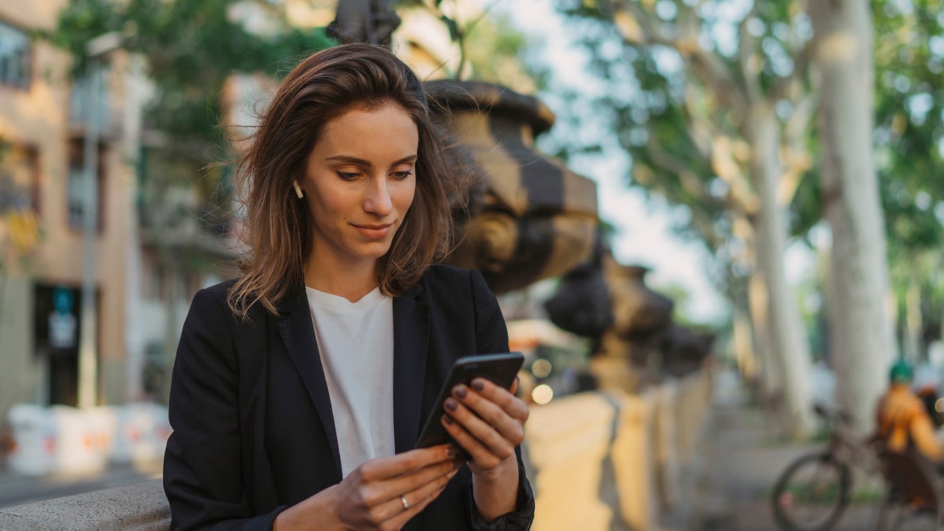 woman in a urban environment holding her smartphone, using seat connect feature.