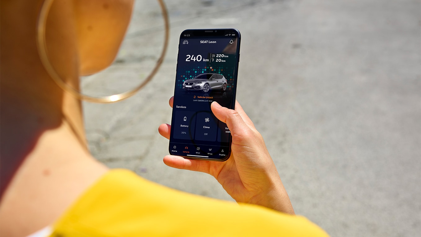 A person holding a smartphone using the my seat app, a feature of seat connect, for remote access and vehicles features.