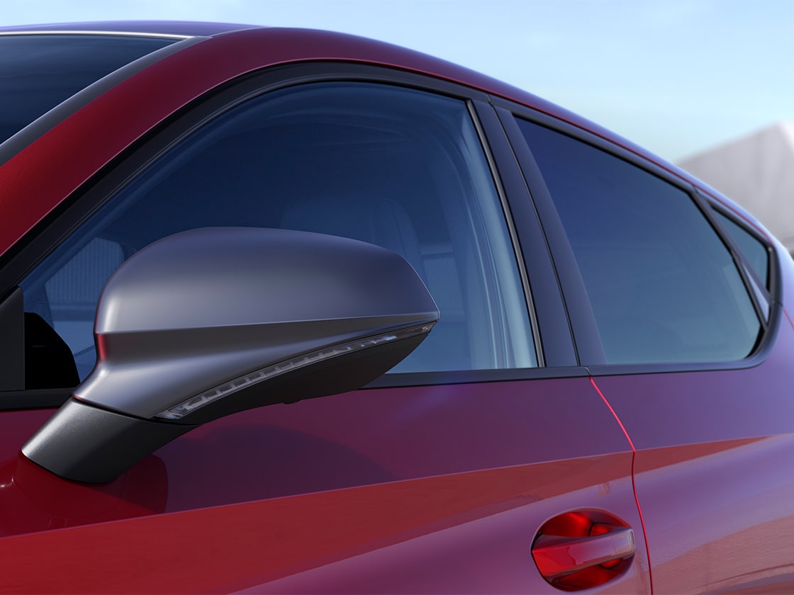 Side view of a SEAT Leon 5D in red parked in a sunny, outdoors environment that highlights the exterior details of the FR Pack.