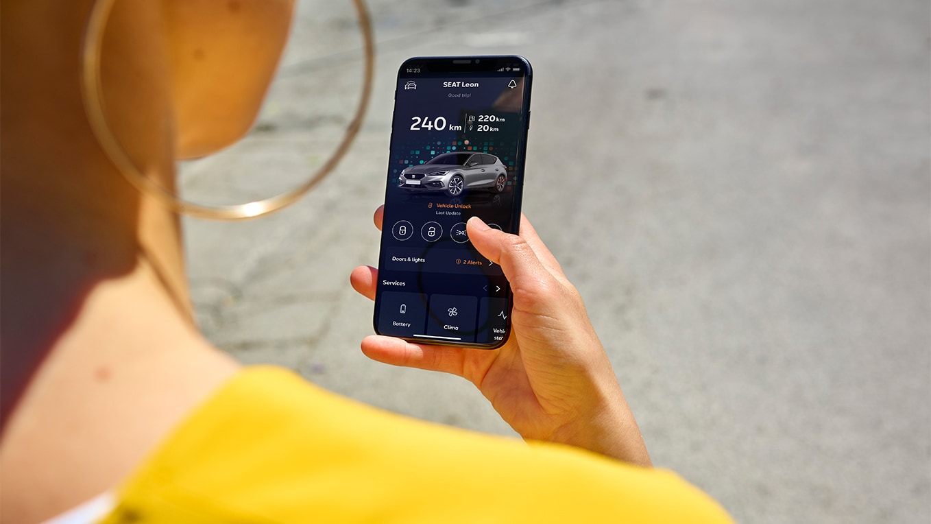 A person holding a smartphone using the my seat app, a feature of seat connect, for remote access and vehicles features.