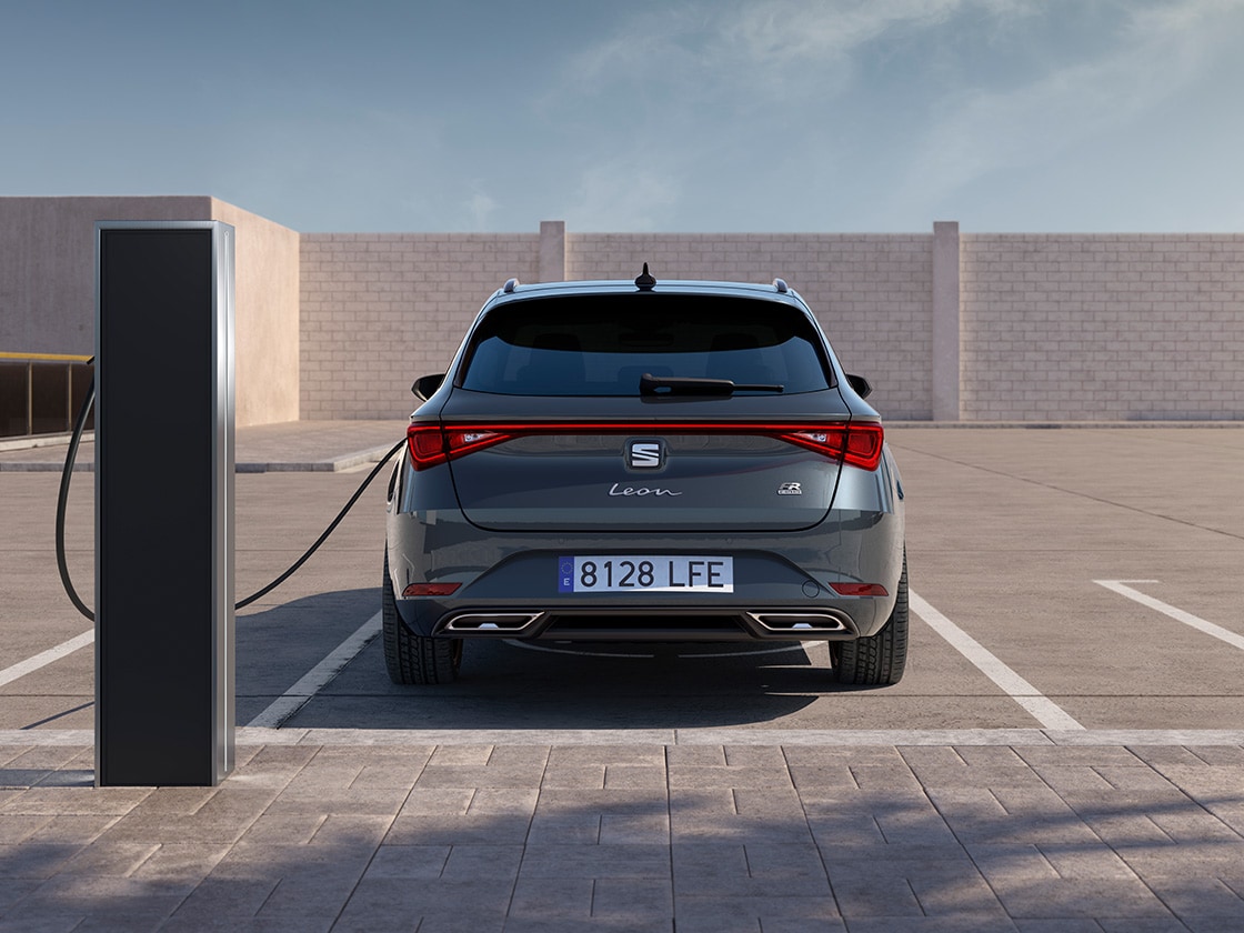 Rear view of a manhattan grey SEAT Leon NF Sportstourer charging in an outdoor parking space.