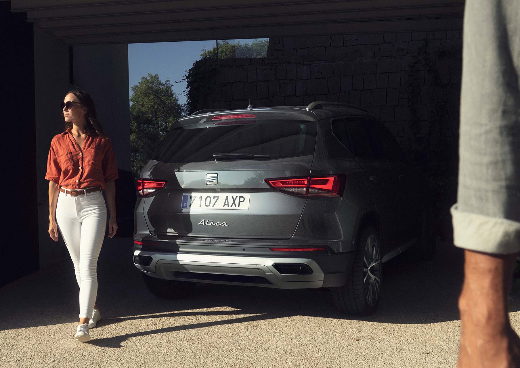 A woman standing next to a SEAT Ateca in graphite grey colour with full rear lead lights