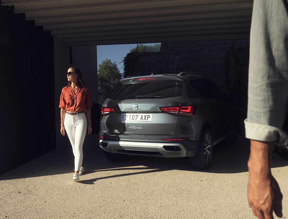woman standing next to the new seat ateca graphite grey with full rear lead lights