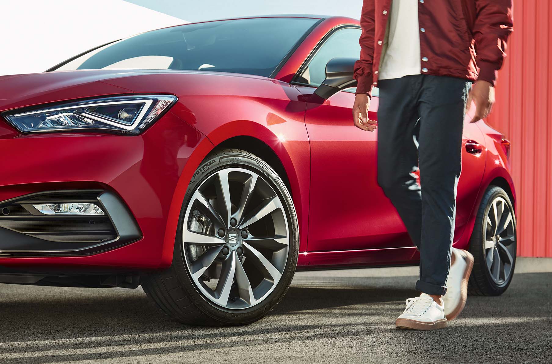 man standing next to seat leon desire red with cosmo grey alloy wheels