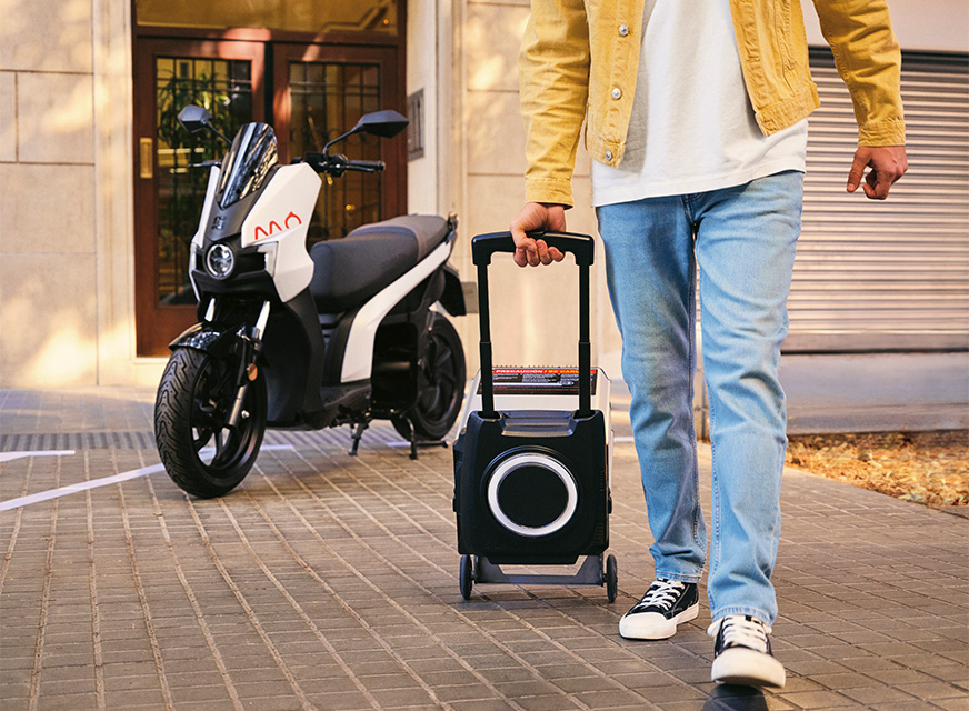 a man carrying the battery of his removable electric scooter