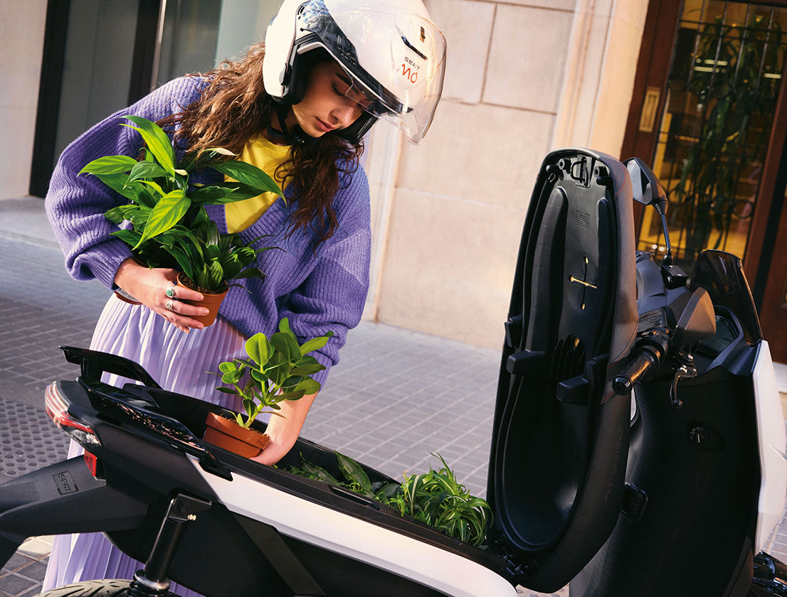a girl putting plants in her scooter trunck