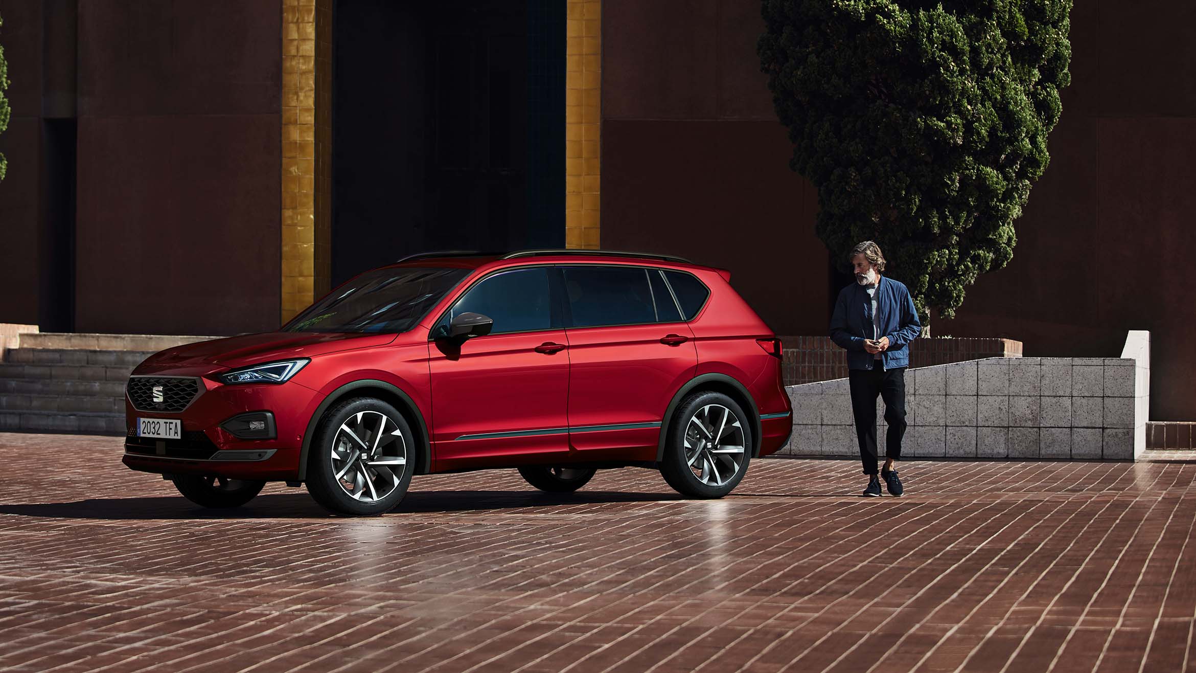 Man walking behind the SEAT Tarraco FR merlot red colour with cosmo grey alloy wheels