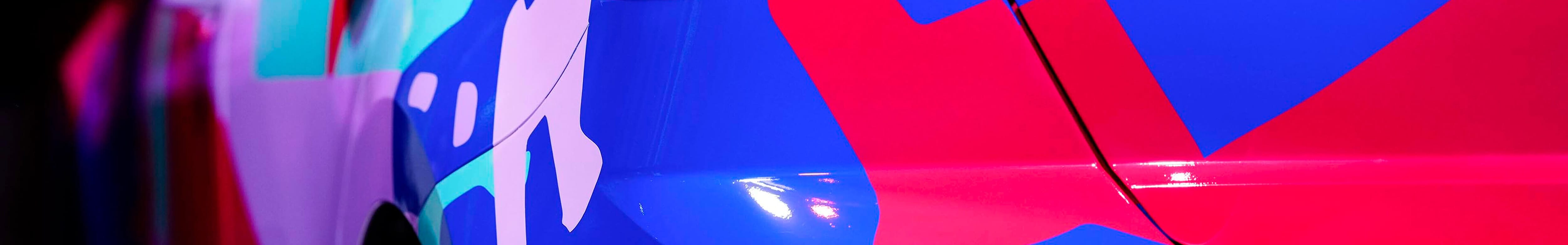 Close-up of the rear side of a SEAT car with a vibrant, colorful design featuring abstract shapes in red, blue, purple, and green.