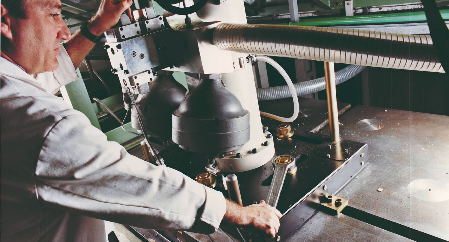 A man in white coat carefully operating a piece of industrial machinery.