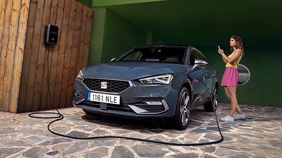 Mild hybrid electric vehicle seat leon sportstourer in red parked in the shadows by a building