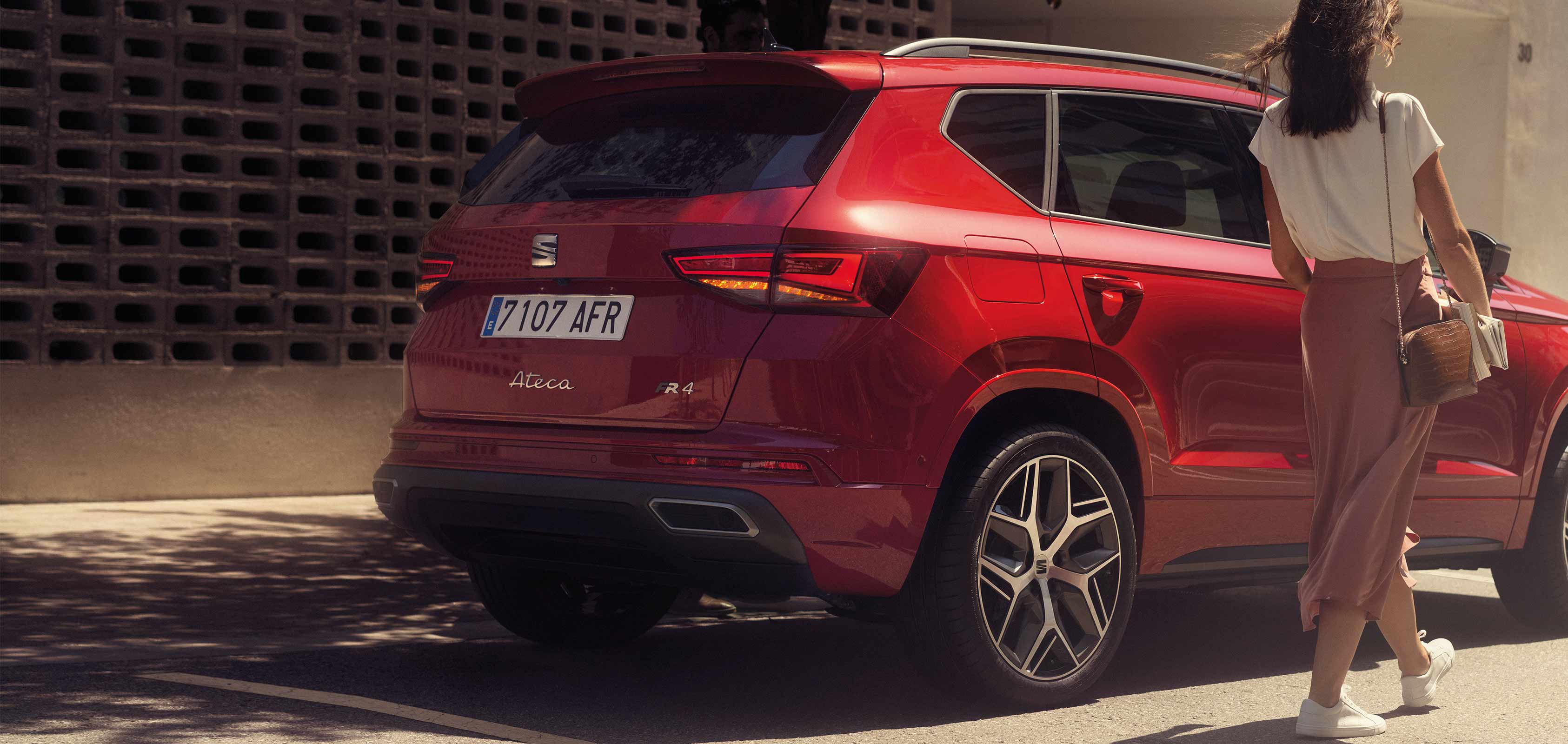 Girl standing next to SEAT Ateca SUV velvet red colour