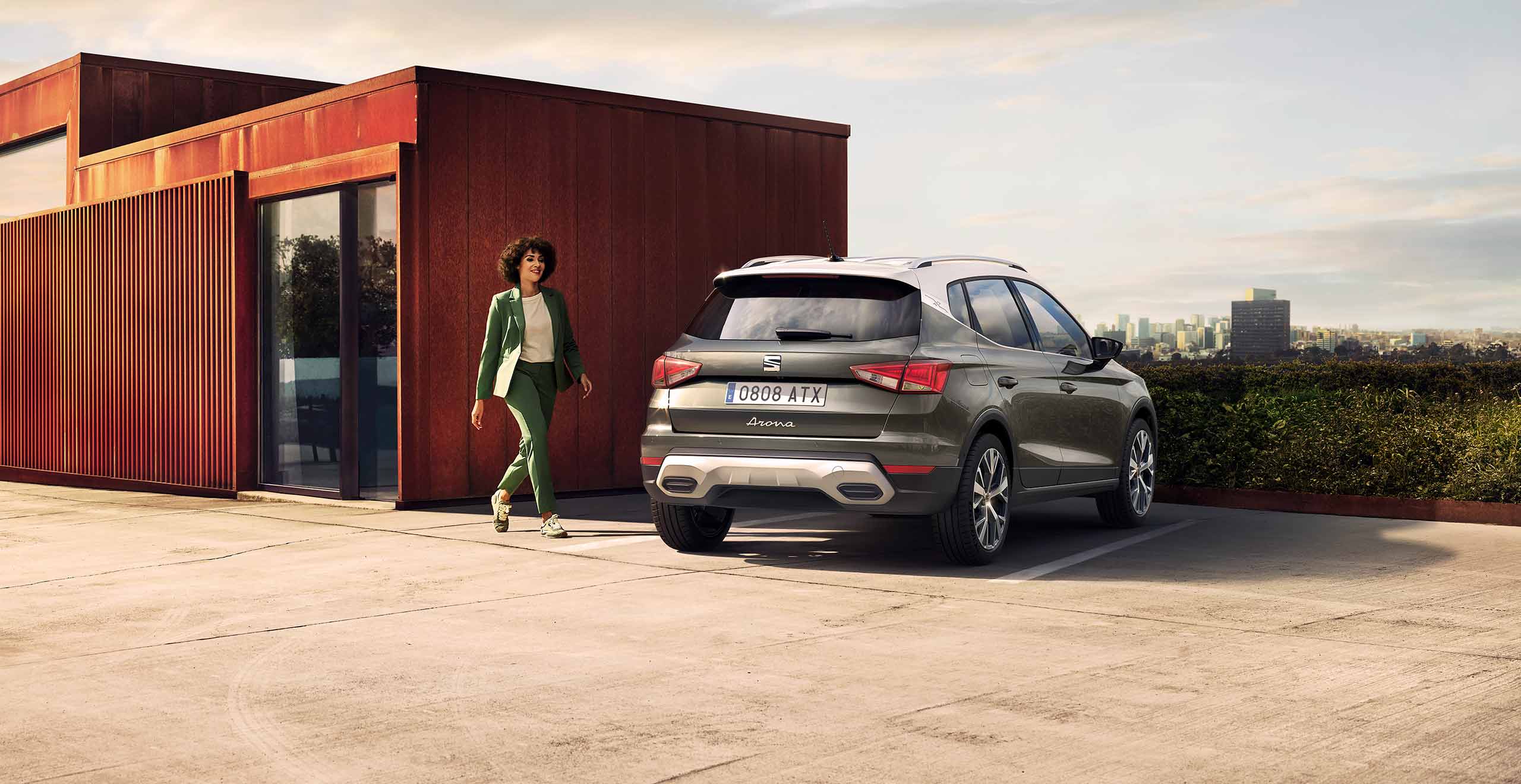 Woman walking to SEAT Arona dark camouflage colour with exhaust pipes 
