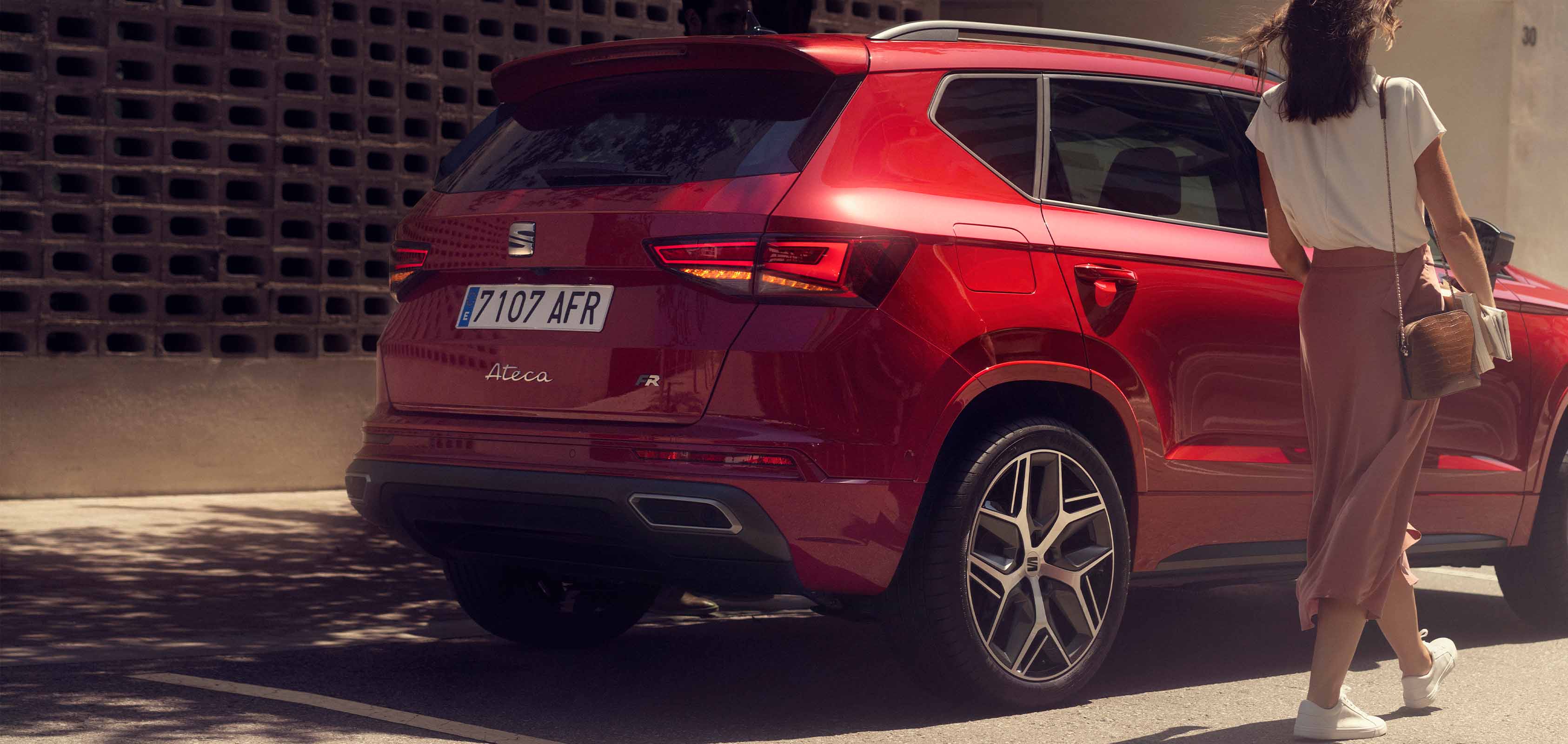 Girl standing next to SEAT Ateca SUV velvet red colour