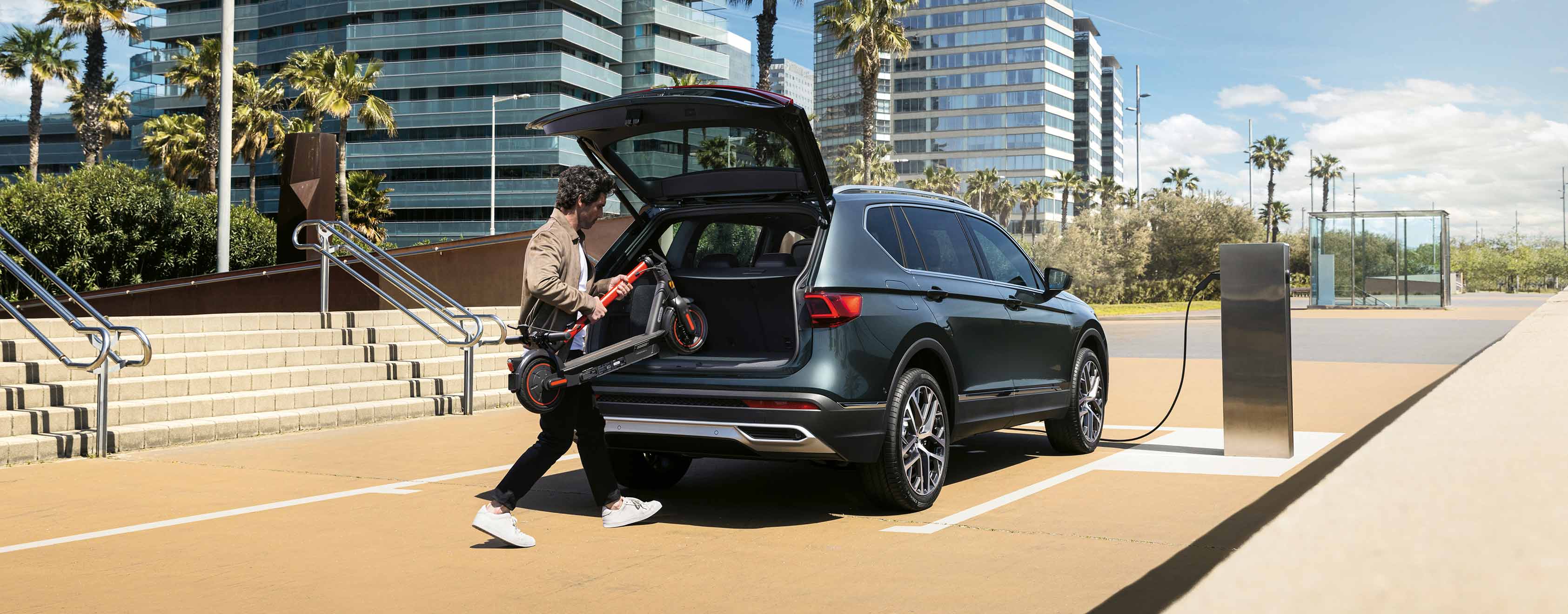 Man loading the trunk of a SEAT Tarraco in black during electric charging