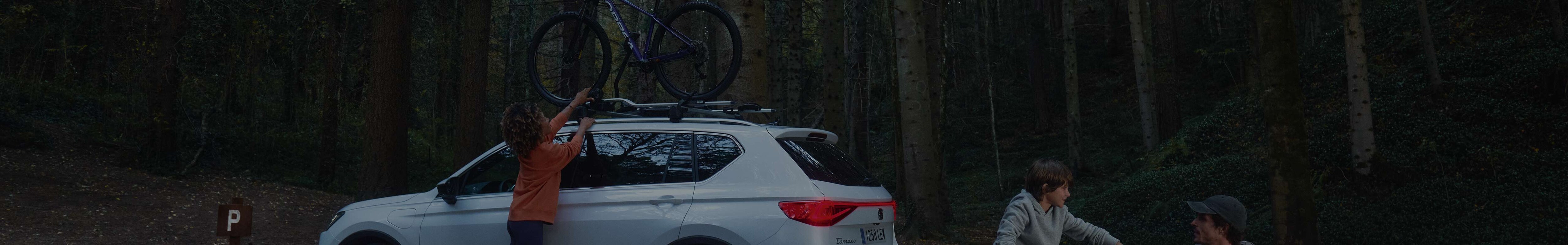 Man standing next to SEAT Tarraco atlantic blue colour with a ski rack.