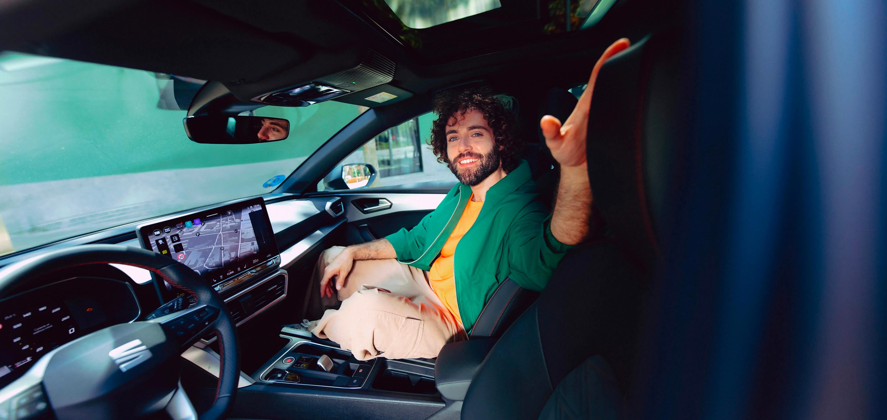 Man enjoying the interior of a SEAT Leon NF 5D e-HYBRID, highlighting modern dashboard and ergonomic seating design.