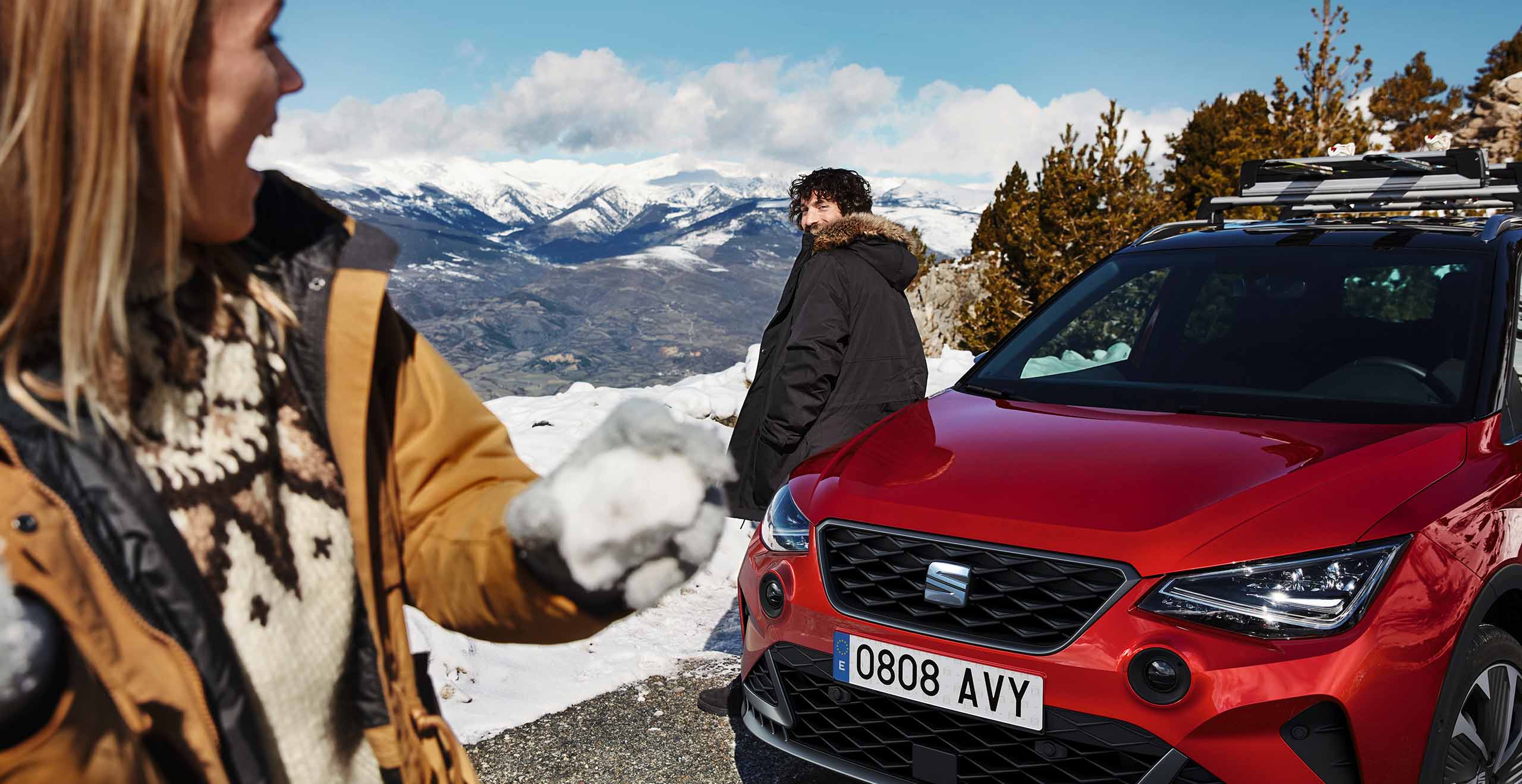 Front view of a SEAT Leon, while a couple is having a snowball fight 