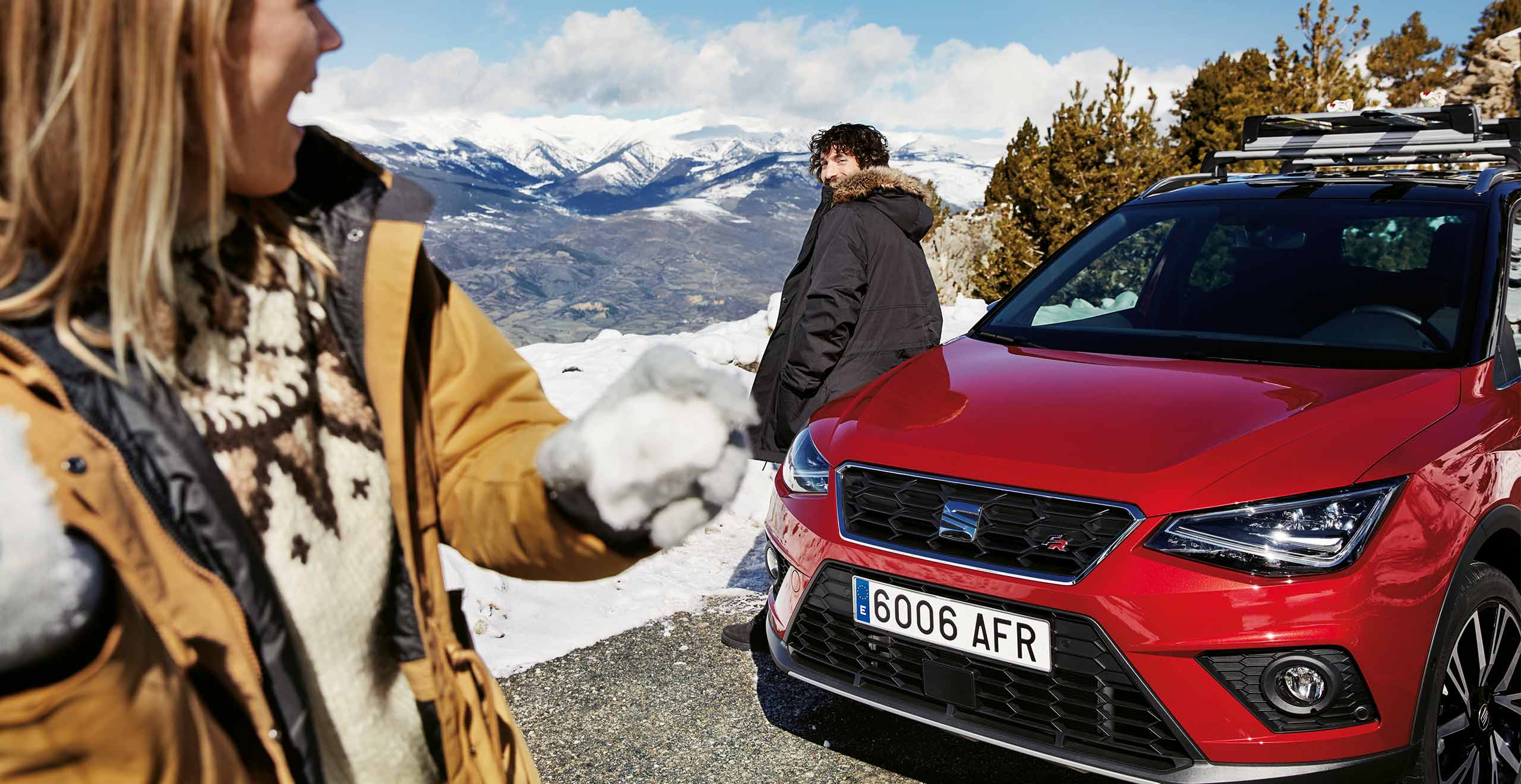 Front view of a SEAT Leon, while a couple is having a snowball fight 