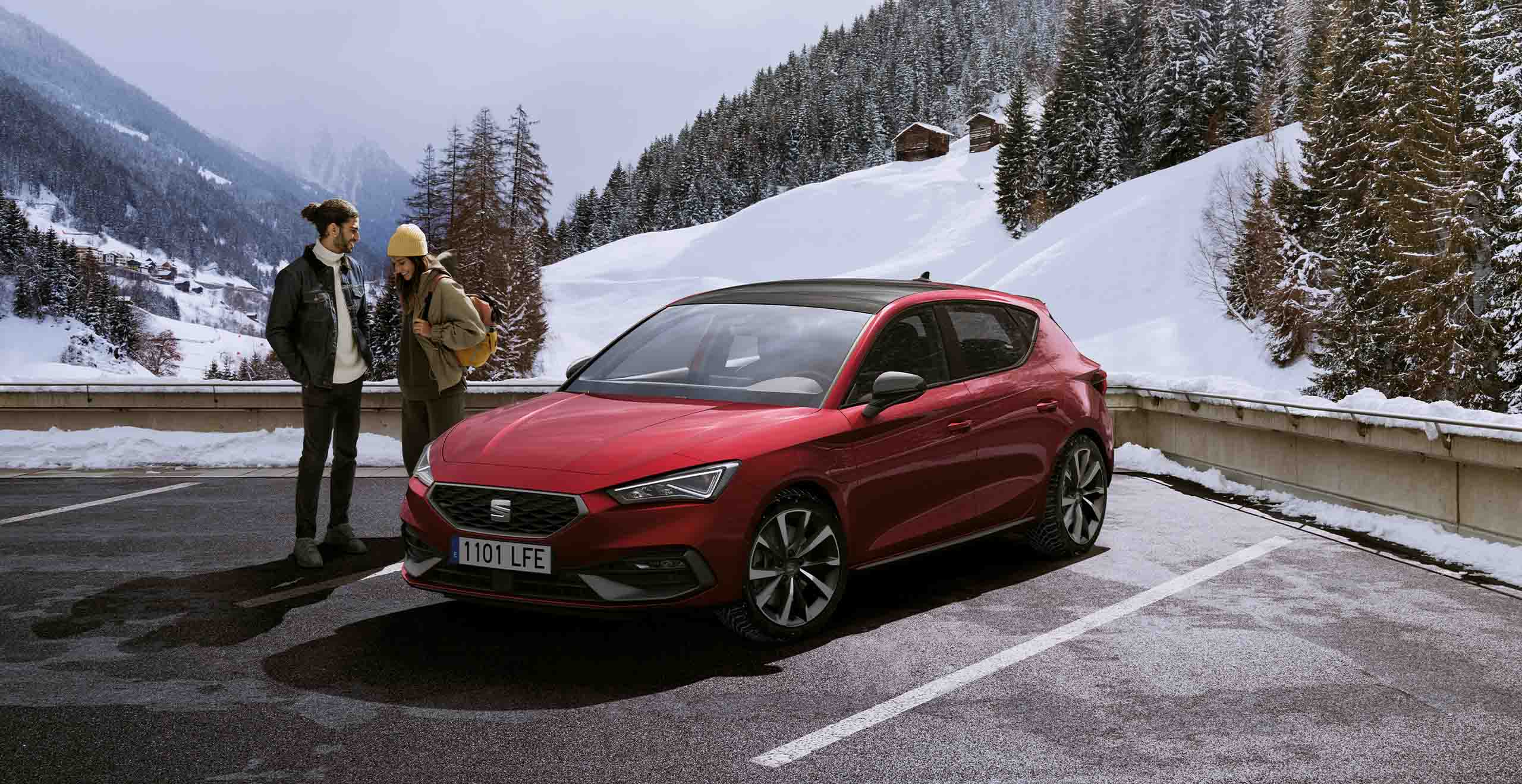 Front view of a SEAT Leon, while a couple is having a snowball fight 