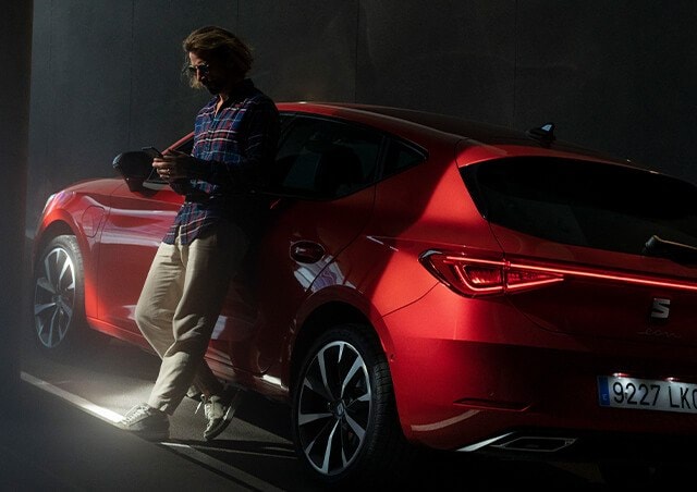 Red SEAT Leon parked on an underground ramp, with the driver checking connectivity status via the VIN checker.