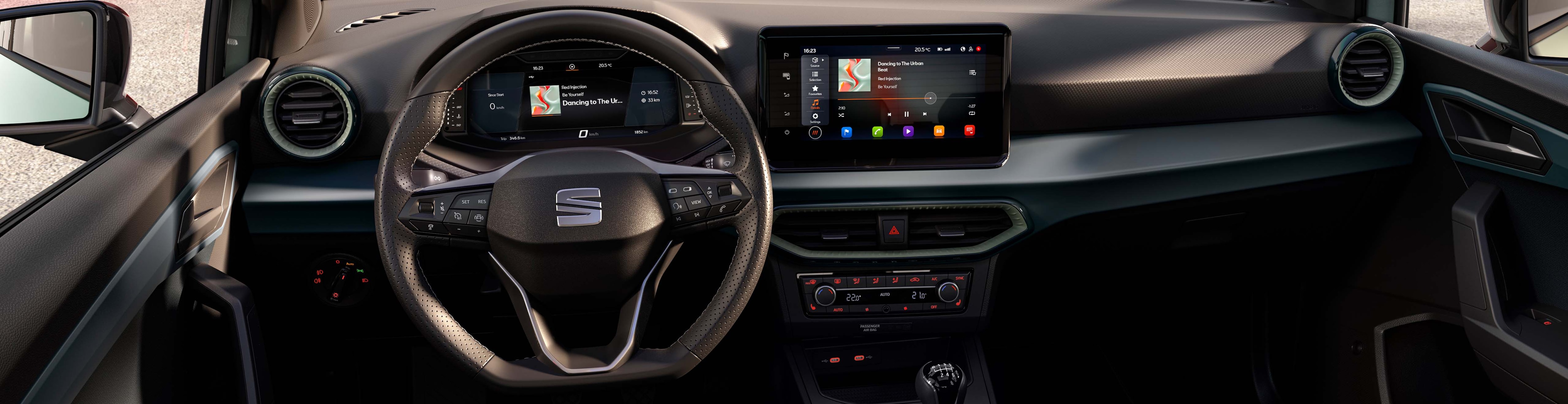 A wide view of the interior of a SEAT Ibiza car, showing the dashboard, steering wheel, digital driver's display, and the central infotainment touchscreen. The car has a manual transmission shift lever.