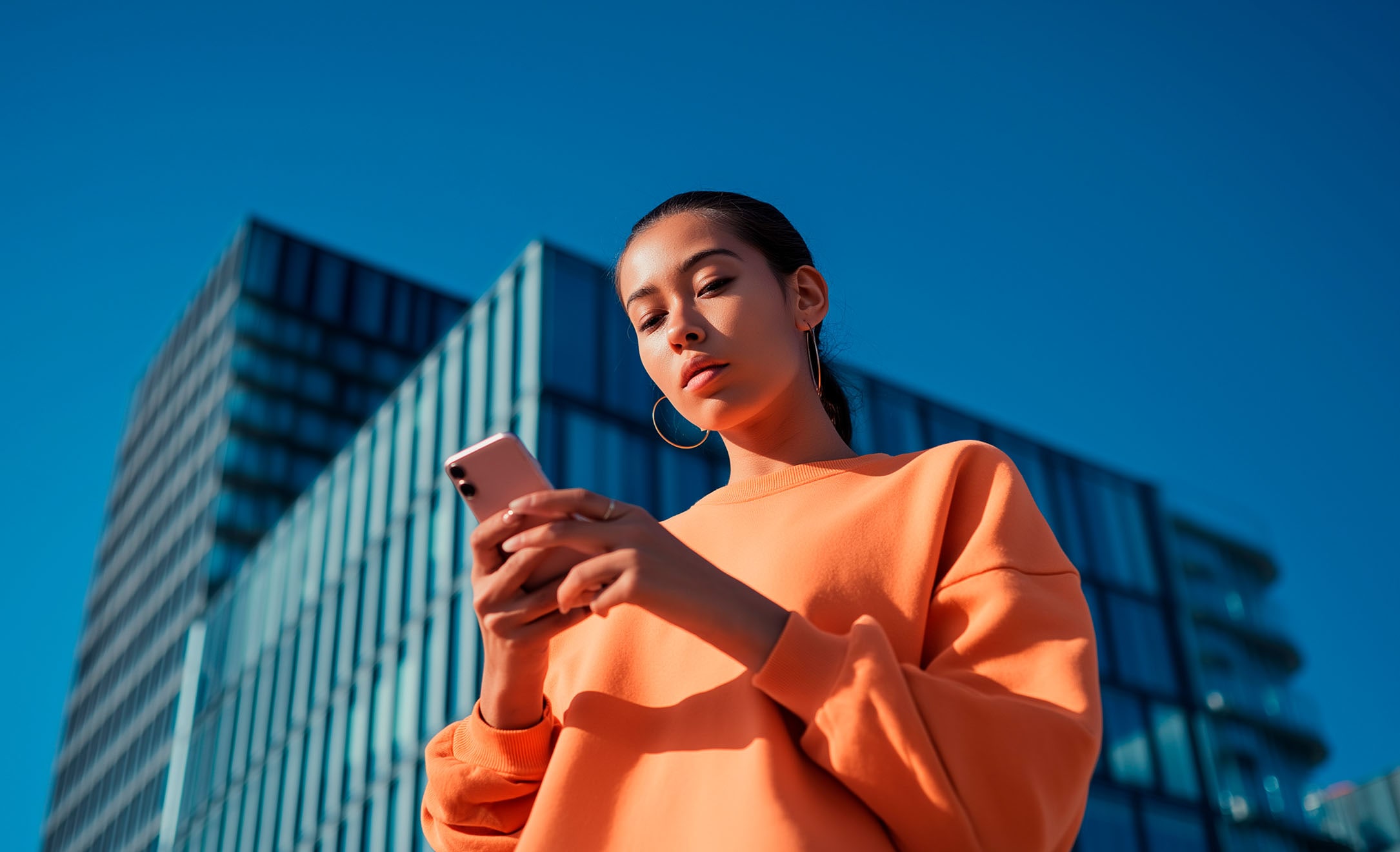 A woman using the My SEAT App on a smartphone outdoors, illustrating remote vehicle access, digital services, and seamless connectivity for modern urban mobility.