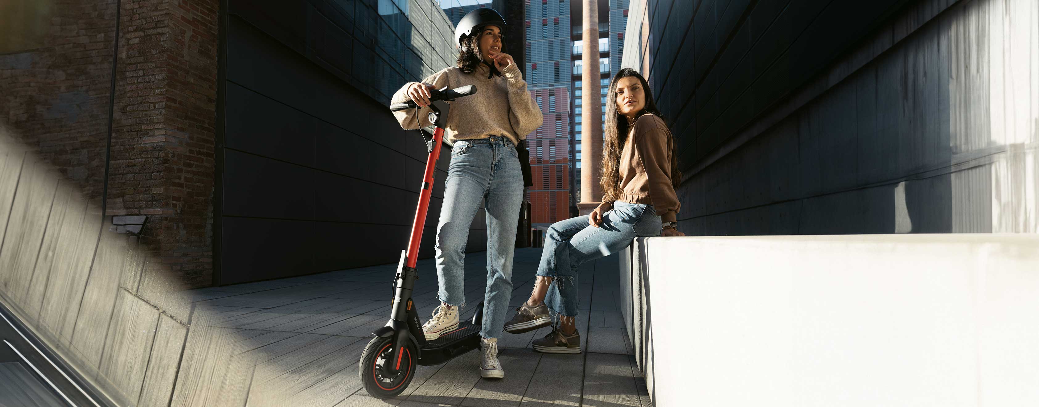 two girls riding a seat mo 65 kickscooter in the city